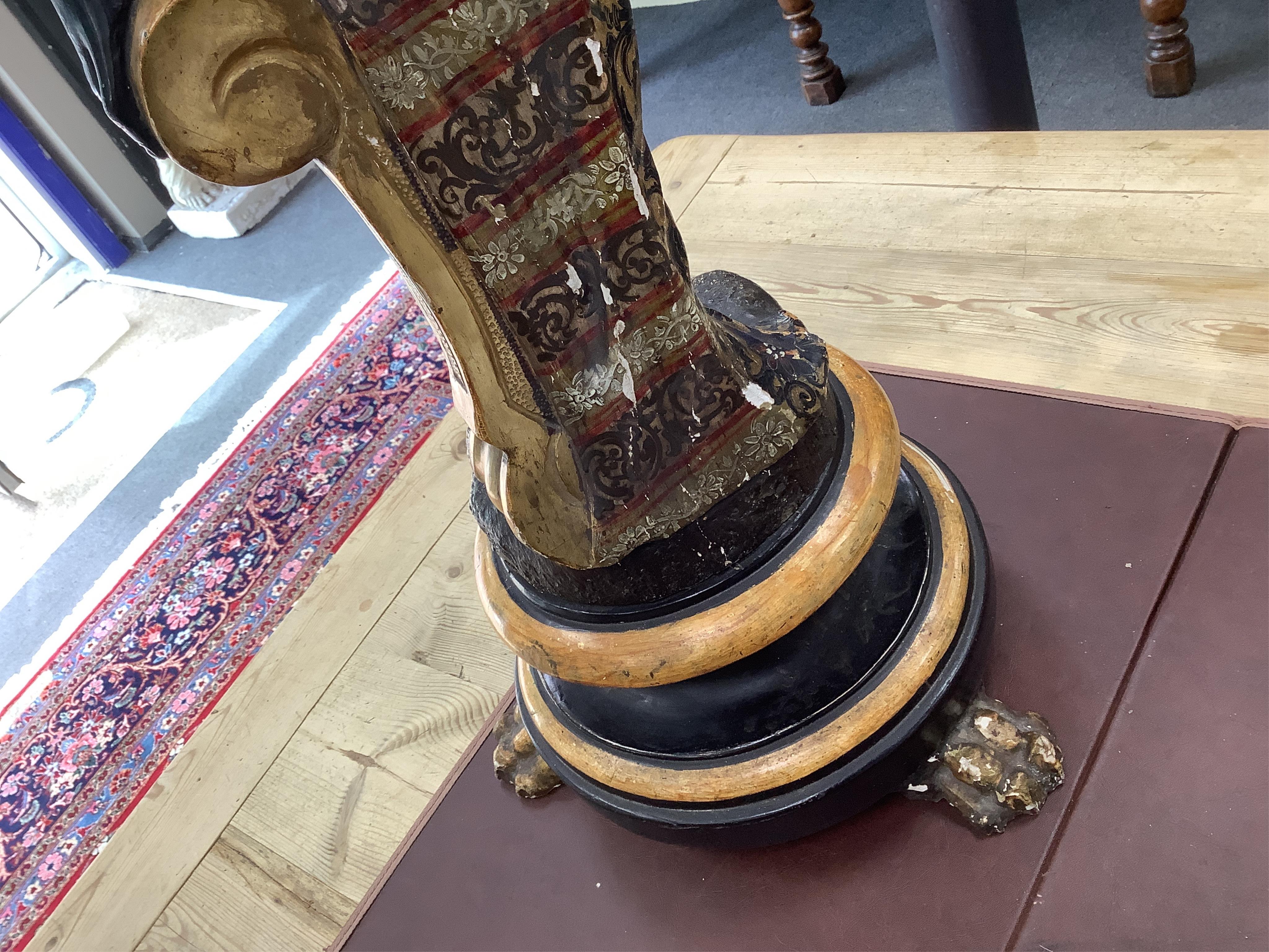 A 19th century Italian carved wood and composition polychrome painted blackamoor torchere, modelled standing with one arm holding a scroll pillar on waisted circular base and lions paw feet, 106cm high